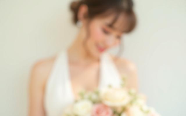 Pengantin berwajah ceria dengan solekan natural dan dandanan rambut 'updo' moden, memegang sejambak bunga.